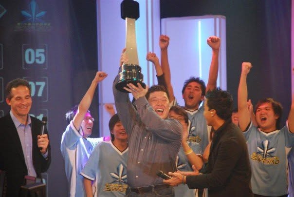 GBR celebrating on stage with a trophy.
